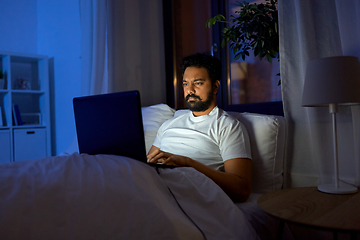 Image showing indian man with laptop in bed at home at night