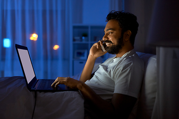 Image showing indian man with laptop calling on phone at night