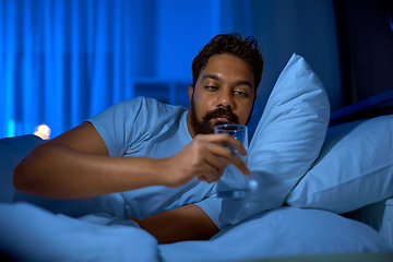 Image showing indian man drinking water in bed at night