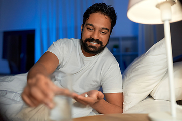 Image showing indian man with medicine and water in bed at night