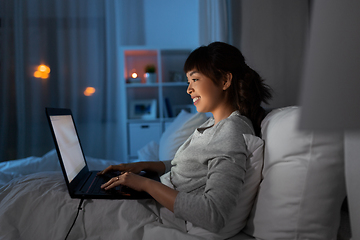 Image showing woman with laptop in bed at home at night