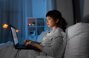 Image showing woman with laptop in bed at home at night