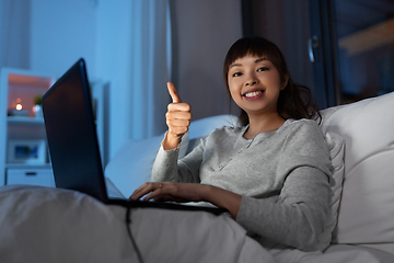 Image showing woman with laptop in bed at night shows thumbs up