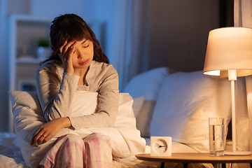 Image showing stressed asian woman sitting on bed at night