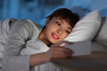 Image showing asian woman with smartphone in bed at night