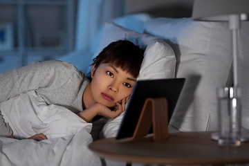 Image showing asian woman with tablet pc in bed at home at night