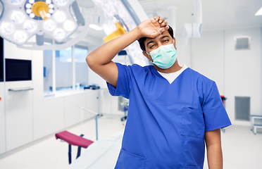 Image showing tired indian male doctor in blue uniform and mask