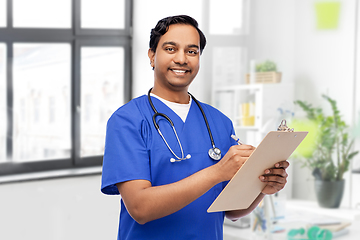 Image showing male doctor writing medical report on clipboard