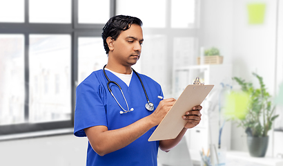 Image showing male doctor writing medical report on clipboard