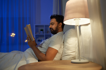 Image showing indian man reading book in bed at night