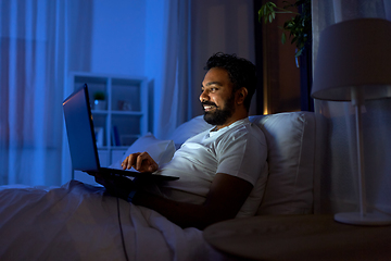 Image showing indian man with laptop in bed at home at night