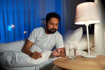 Image showing indian man with medicine and water in bed at night