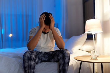 Image showing stressed indian man sitting on bed at night