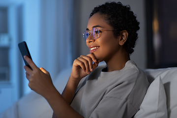 Image showing african woman with smartphone in bed at night