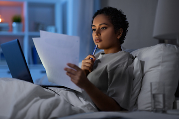 Image showing woman with laptop and papers in bed at night