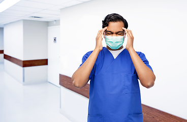 Image showing stressed indian doctor in mask having headache