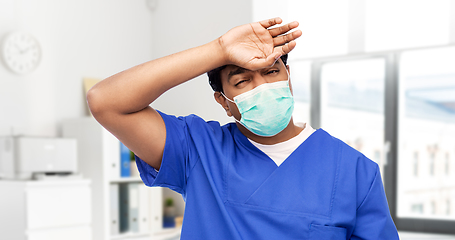 Image showing tired indian male doctor in blue uniform and mask