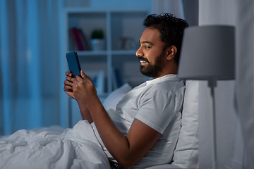 Image showing indian man with tablet pc in bed at home at night