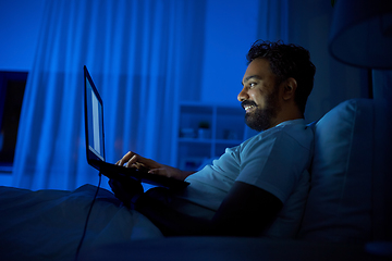 Image showing indian man with laptop in bed at home at night