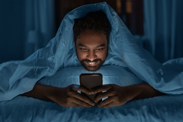 Image showing indian man with smartphone in bed at home at night