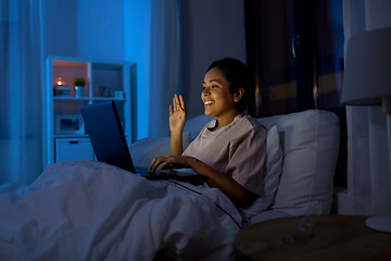 Image showing woman having video call on laptop in bed at night