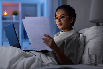 Image showing woman with laptop and papers in bed at night