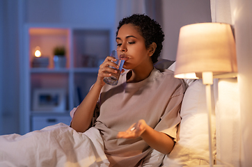 Image showing woman with medicine and water in bed at night