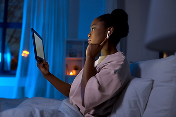 Image showing woman with tablet pc in earphones in bed at night