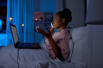 Image showing woman with laptop calling on phone in bed at night