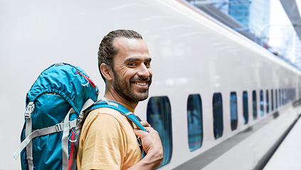 Image showing smiling man with backpack traveling over train