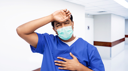 Image showing tired indian male doctor in blue uniform and mask