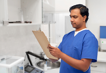 Image showing male doctor writing medical report on clipboard
