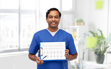 Image showing smiling male doctor with cardiogram on clipboard