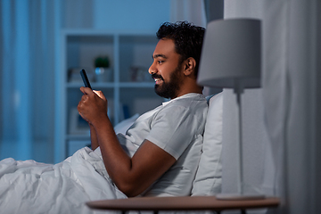 Image showing indian man with smartphone in bed at home at night