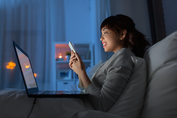 Image showing asian woman with smartphone in bed at night