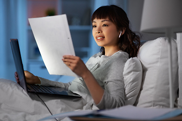 Image showing woman with laptop and papers in bed at night