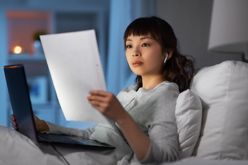 Image showing woman with laptop and papers in bed at night