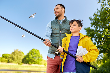 Image showing happy smiling father and son fishing on river