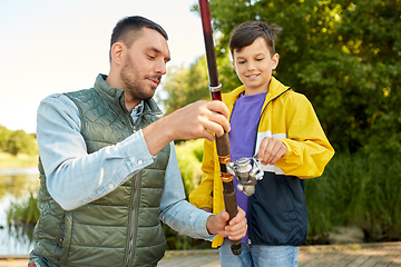 Image showing happy smiling father and son fishing on river