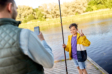 Image showing father photographing son with fishing rod on river