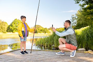 Image showing father photographing son with fishing rod on river