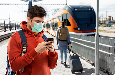 Image showing man in mask with smartphone traveling by train