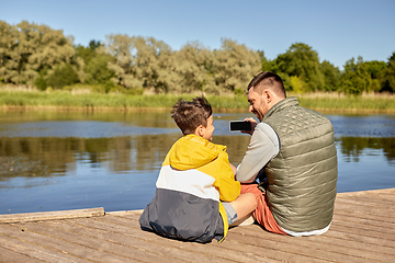 Image showing father and son taking selfie with phone on river