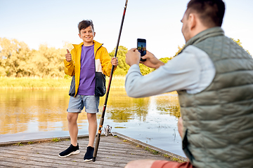 Image showing father photographing son with fishing rod on river