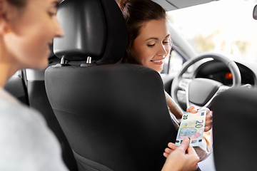 Image showing female car driver taking money from passenger