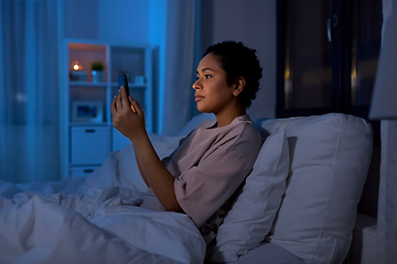 Image showing woman with smartphone in bed at home at night