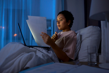 Image showing woman with laptop and papers in bed at night