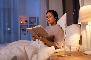 Image showing young woman reading book in bed at home