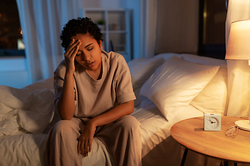 Image showing stressed african woman lying in bed at night