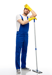 Image showing tired male cleaner cleaning floor with mop